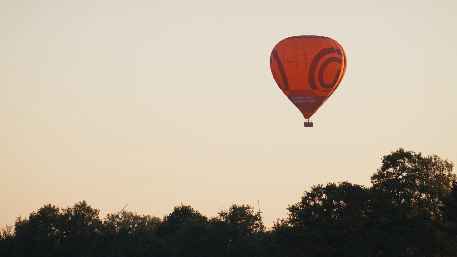 Luchtballon boven de bomen bij zonsondergang